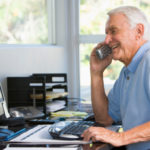 senior_working_at_computer_on_phone1
